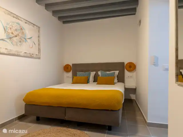 Slaapkamer met kingsize bed, badjassen, ladenkastje en spiegel. Deze kamer heeft een ensuite badkamer.